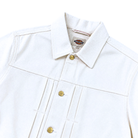The Selvedge Pleated Denim Jacket in white features gold buttons, a classic collar, visible stitching, and a small logo tag inside the collar.