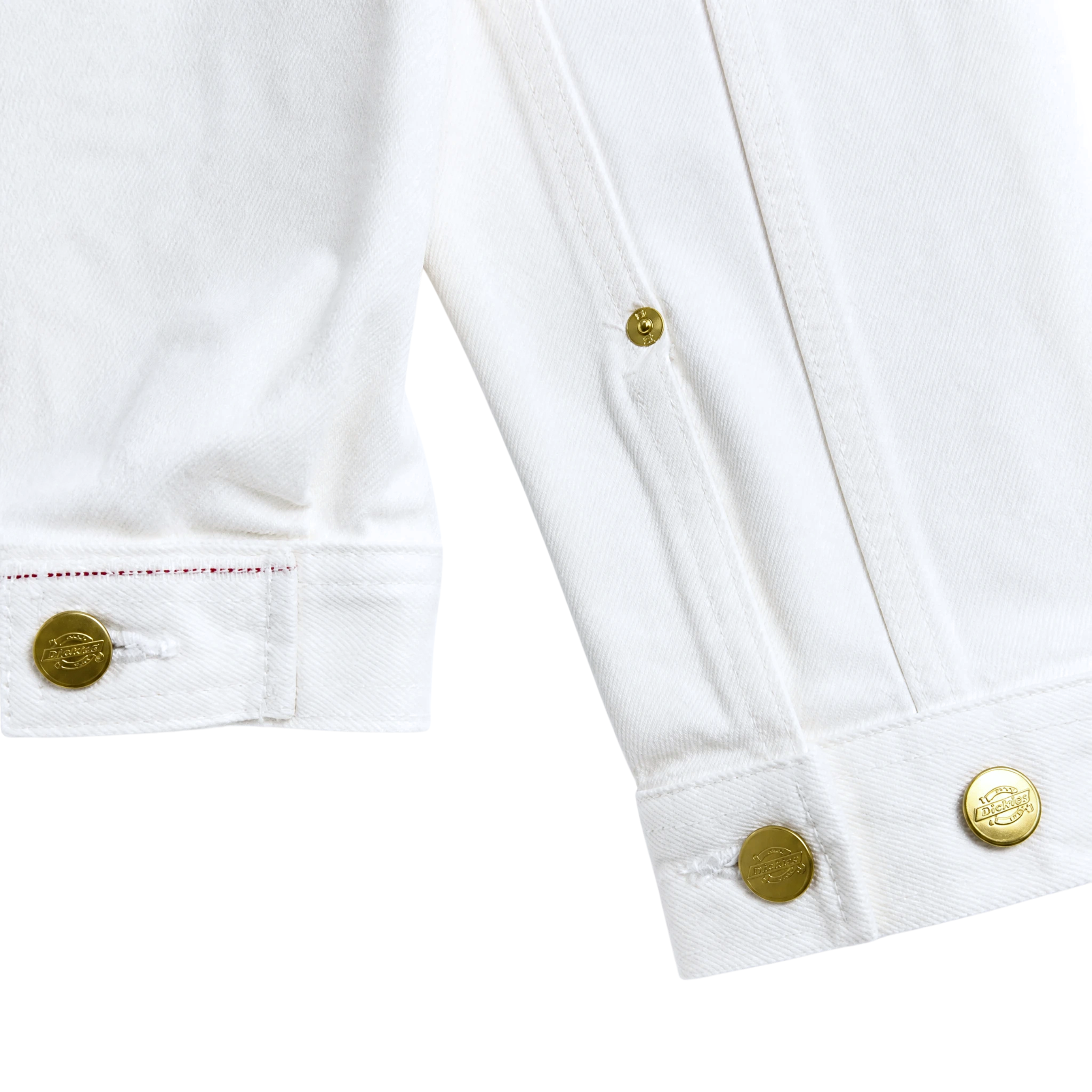 Close-up of the cuffs and lower edge of the Selvedge Pleated Denim Jacket in white, featuring gold logo-embossed buttons and detailed visible stitching.