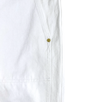 Close-up of Selvedge Double Knee Denim Jeans in white, showing the vertical seam, a small brass rivet, and textured fabric with detailed stitching—hallmarks of Dickies workwear.