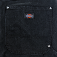 Close-up of a black fabric pocket with silver rivets and a sewn-on Dickies logo patch, showcasing the durable construction of the Double Knee Canvas Shorts in black.