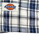 Close-up of the Springdale Short-sleeve Button-up Shirt in egret and blue, featuring a plaid cotton-linen blend and a sewn-on Dickies label with yellow, red, and blue logo. Perfect details on this stylish shirt.
