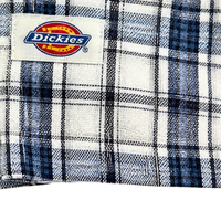Close-up of the Springdale Short-sleeve Button-up Shirt in egret and blue, featuring a plaid cotton-linen blend and a sewn-on Dickies label with yellow, red, and blue logo. Perfect details on this stylish shirt.