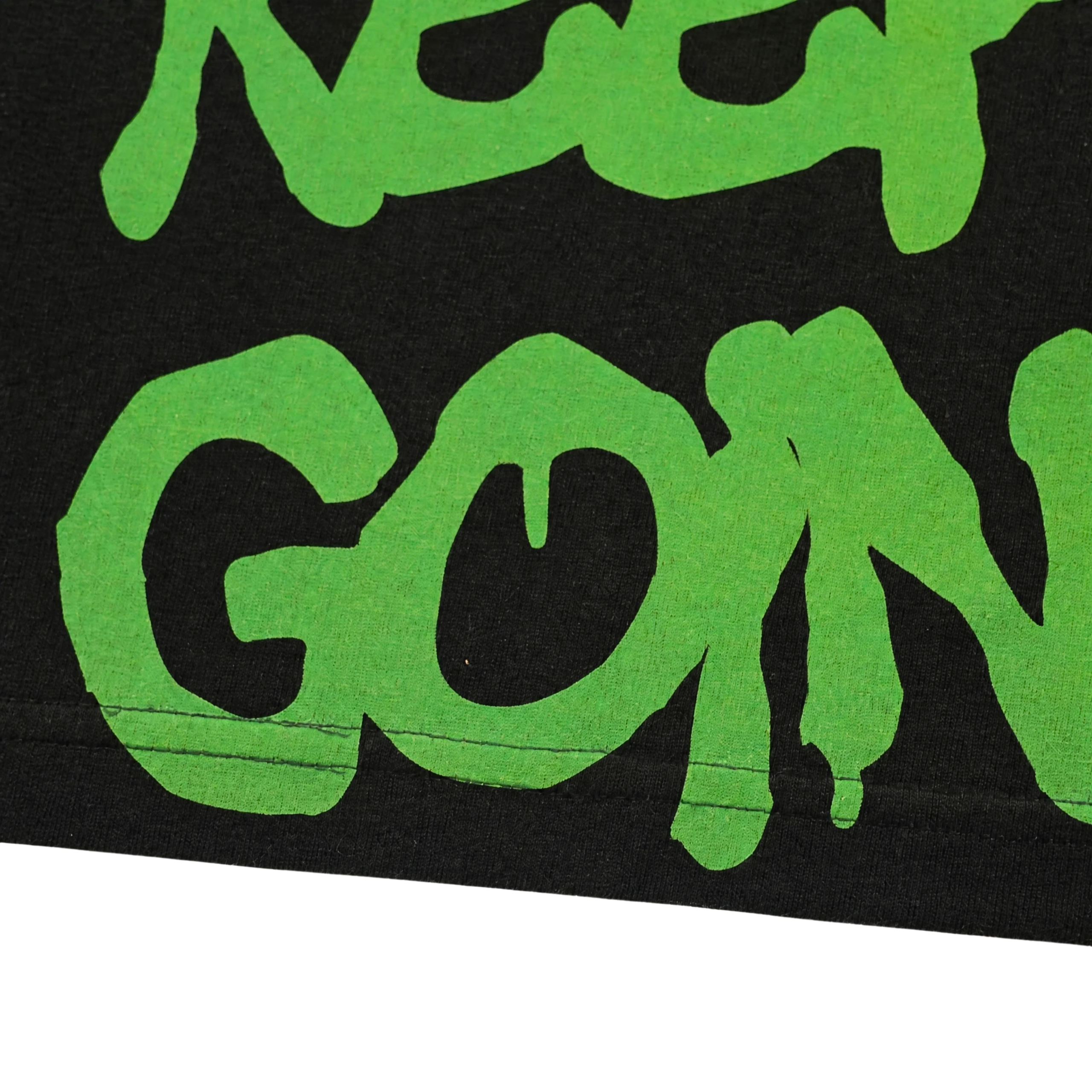 Close-up of green, graffiti-style text on black shows "KEEP GOIN'"—perfect for the Keep Goin' Tee in black, an oversized streetwear piece inspired by San Francisco's Mission District energy.