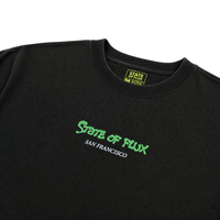 The Keep Goin' Tee in black is a heavyweight cotton, oversized streetwear t-shirt with STATE OF FLUX in green and SAN FRANCISCO in white on the chest, inspired by SF's Mission District. Features a yellow & black collar tag with the brand name and size.