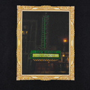 A gold ornate frame surrounds a photo of a vintage theater sign lit with green neon, reading NEW MISSION and THE MISSION CONTINUES—a classic San Francisco Mission District scene—featured on the Keep Goin' Tee in black.