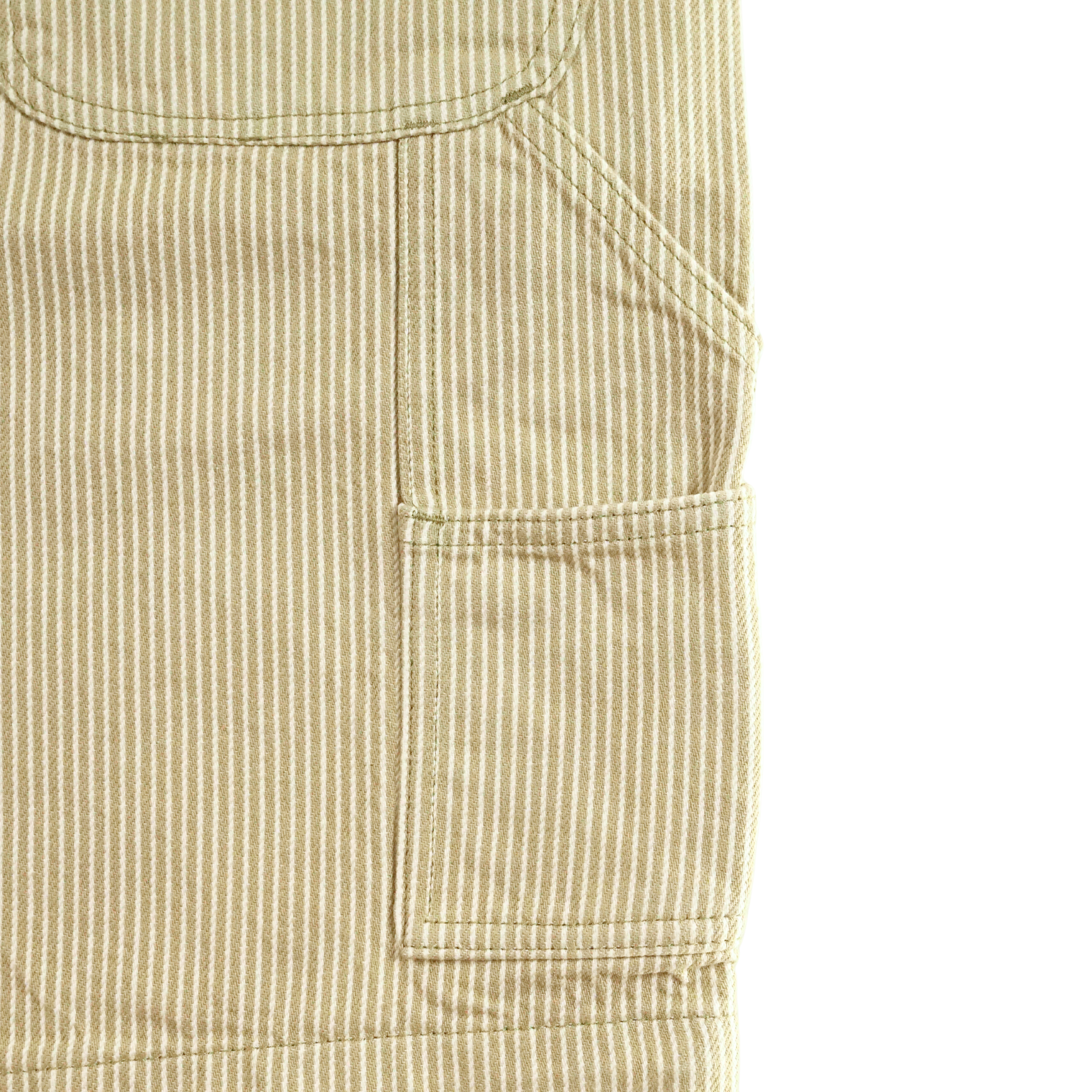 Close-up of beige and white vertically striped fabric with a stitched rectangular pocket and seam details, from Hickory Stripe Carpenter Shorts in eucalyptus, inspired by classic workwear shorts.