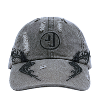 The Everyday Is A Gift Cap in washed black is a gray distressed embroidered baseball cap with black embroidery, featuring a circular logo on the front and black antler-like designs on the brim—this washed denim hat effortlessly elevates any streetwear cap collection.