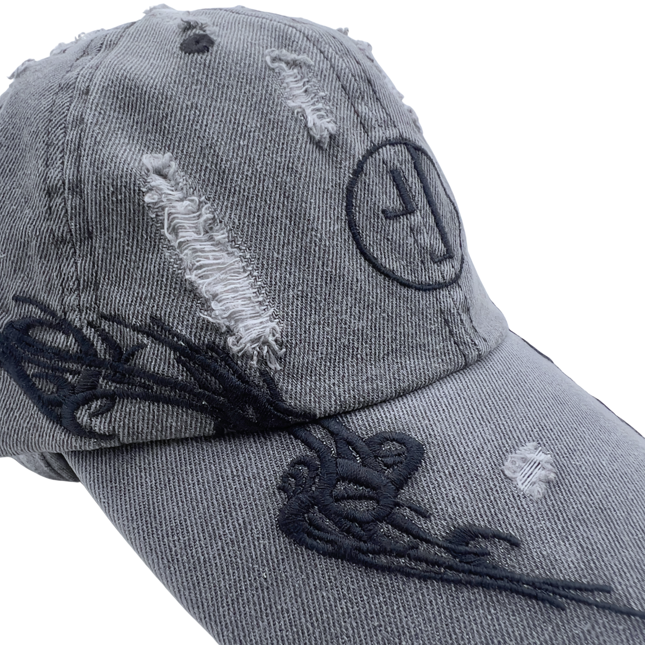 A close-up of the Everyday Is A Gift Cap in washed black—a gray, distressed denim baseball hat featuring torn patches, black embroidered details, and a circular logo on the front—an effortlessly cool accessory perfect for streetwear looks.
