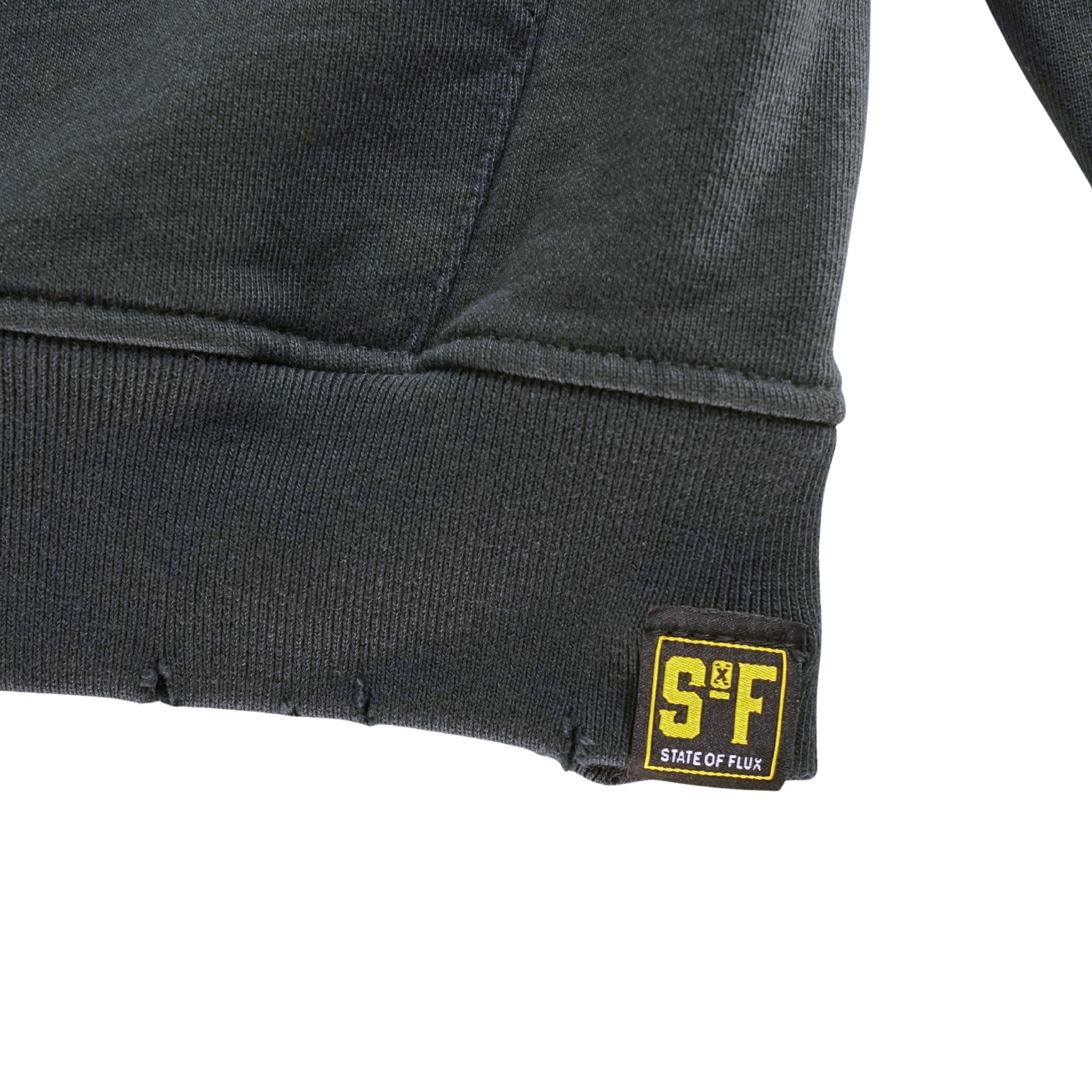 Close-up of the hem of the Today Is The Day Hoodie in distressed faded black and lilac, featuring a small yellow and black S&F STATE OF FLUX fabric tag sewn onto the lower edge.
