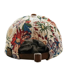 The back view of the Wildflower Strapback Hat in cream and brown reveals a vibrant floral-patterned cap with a brown adjustable strap and metal buckle, featuring a small label that reads State of Flux.