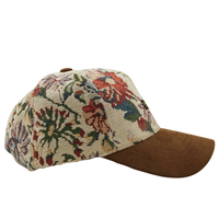 The Wildflower Strapback Hat in cream and brown features a jacquard woven floral crown, a brown suede brim, and is shown from a side view.