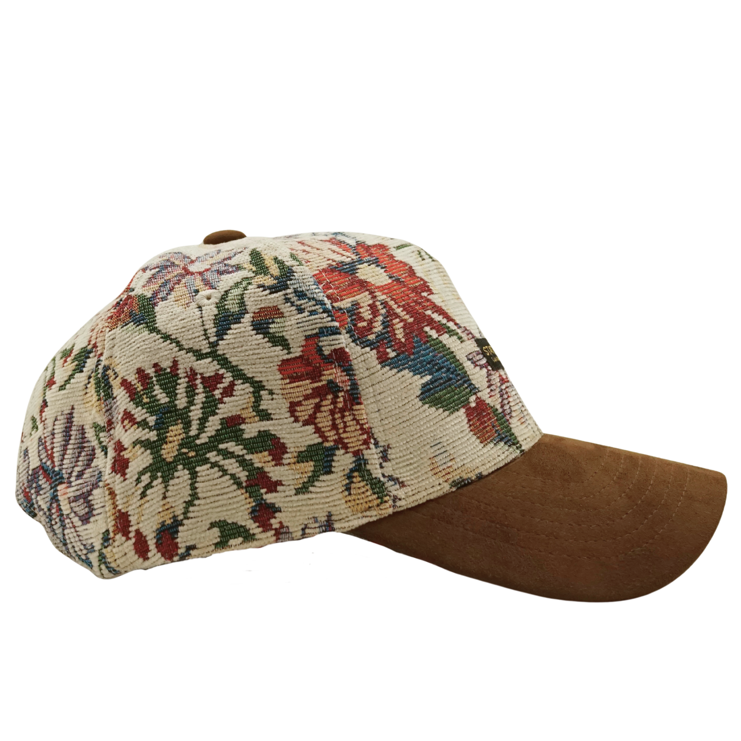 The Wildflower Strapback Hat in cream and brown features a jacquard woven floral crown, a brown suede brim, and is shown from a side view.
