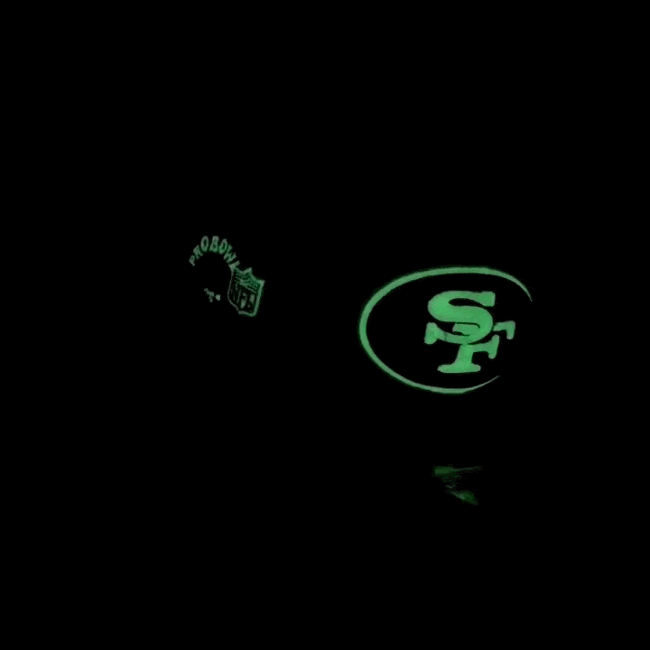 A glowing San Francisco 49ers logo and NFL Pro Bowl emblem stand out against a dark background—perfectly capturing the iconic style of the PREORDER ONLY San Francisco 49ers Surfin’ Garcia 59Fifty Fitted Hat in chrome white and cardinal.