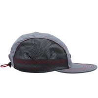 The SOF Active 5-Panel Cap in steel features a gray, lightweight design crafted from water-resistant nylon. It includes a flat brim, black mesh side panels for breathability, red stitching accents, and is finished with a red drawstring closure at the back.