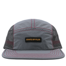 The SOF Active 5-Panel Cap in steel features a gray, lightweight, water-resistant nylon construction with black mesh sides, red stitching, and a rectangular front patch displaying “STATE OF FLUX” in yellow lettering for both comfort and durability.