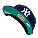A navy and white New York Yankees Seinfeld Corduroy 59Fifty Fitted Hat, shown from beneath to reveal its green underbrim, prominent white NY logo, and size plus authenticity stickers—a classic piece inspired by the iconic Seinfeld New Era cap style.