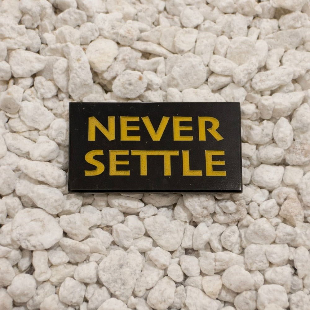 Never Settle Pin in black and yellow