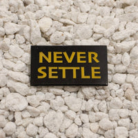 Never Settle enamel pin 1.25in black and yellow soft enamel dual post with black rubber backers